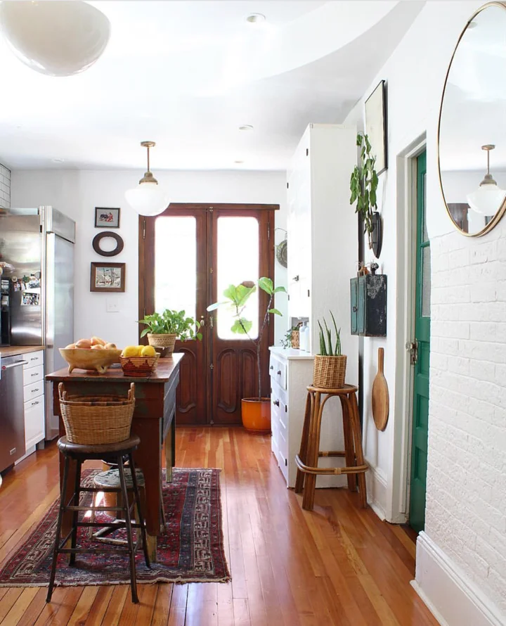 Double doors from Amighini Architectural at the end of the kitchen let in natural light. The kitchen lights date from the 1920s when the were used over a car lot. Mismatched kitchen furniture creates a relaxed and homely space.