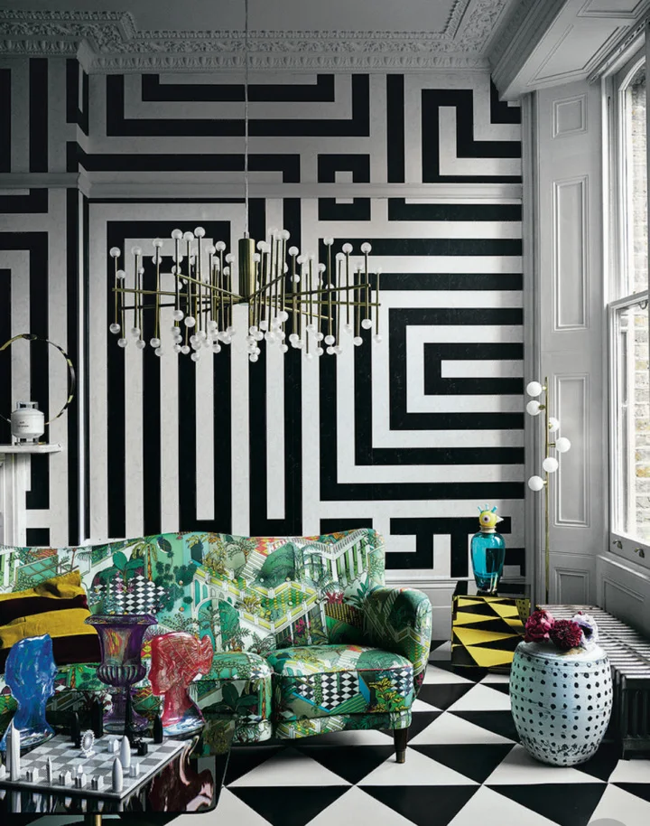 In this image, clashing patterns in the wallpaper, on the floor and on the sofa, along with colourful decorative items and statement lighting, give this room a statement maximalist look. Source. Livingetc.