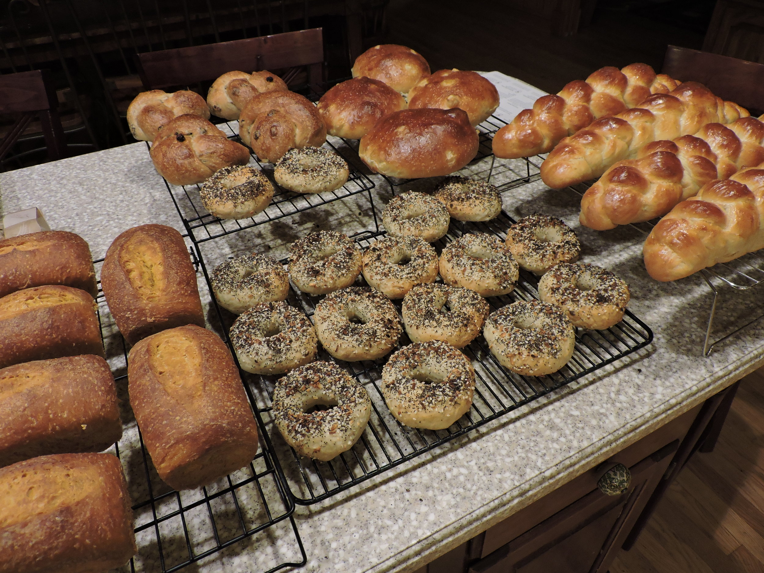  Pumpkin loaves (left), everything bagels (middle), cinnamon raisin knots (back left), apple honey challahs (back right), and plain challah braids (right). 
