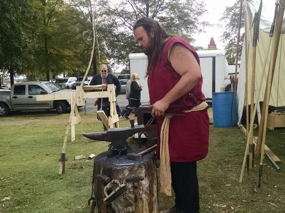 David forging on the anvil with Daniel working a tredle lathe behind.