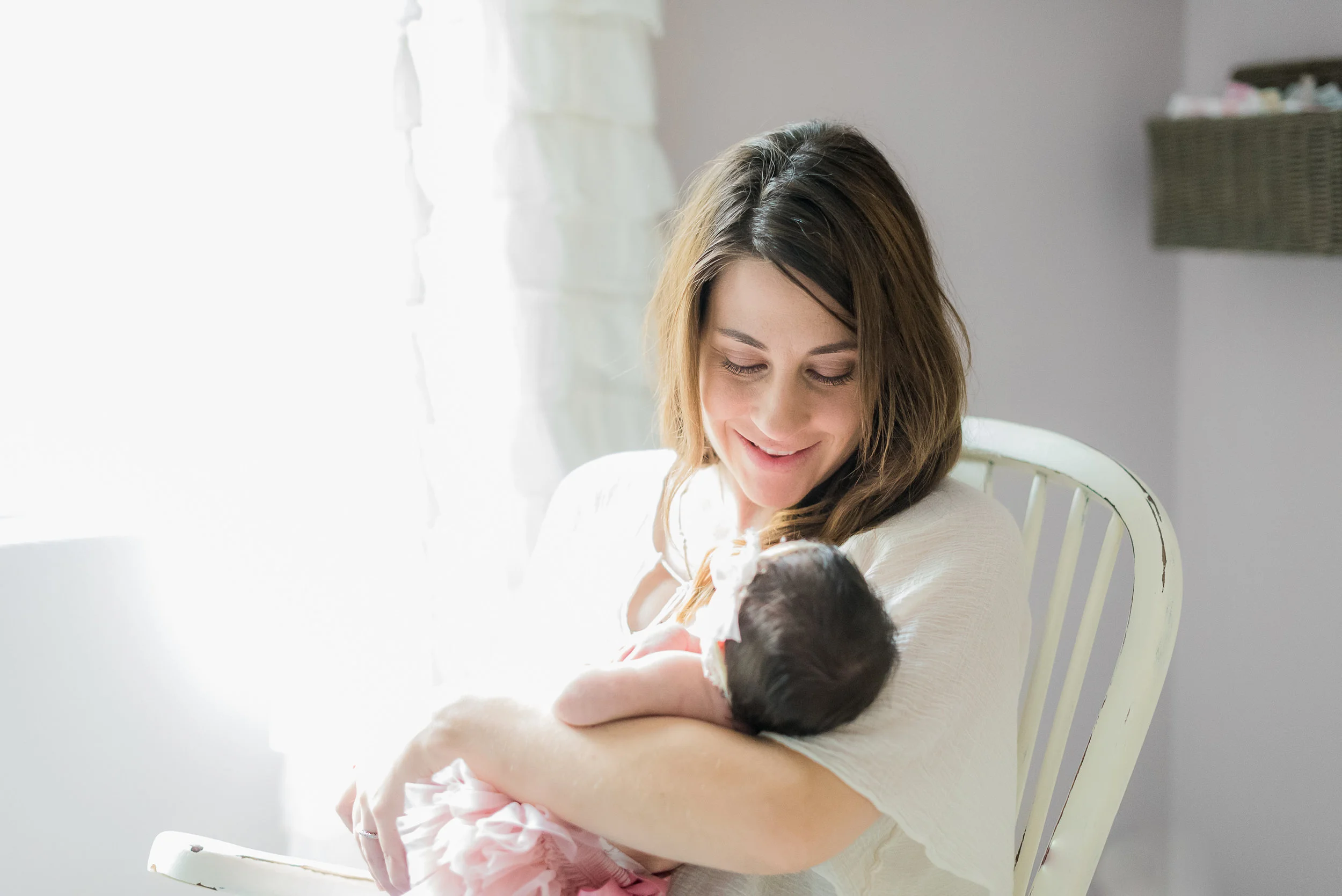 New mom rocking her newborn baby girl in nursery