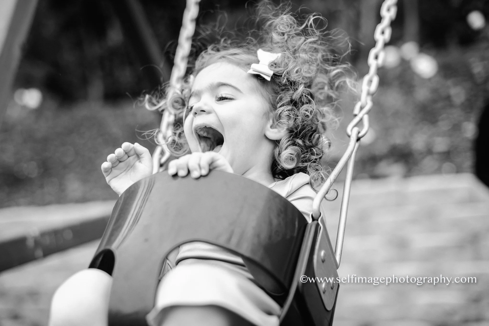 little girl laughing and swinging in her back yard