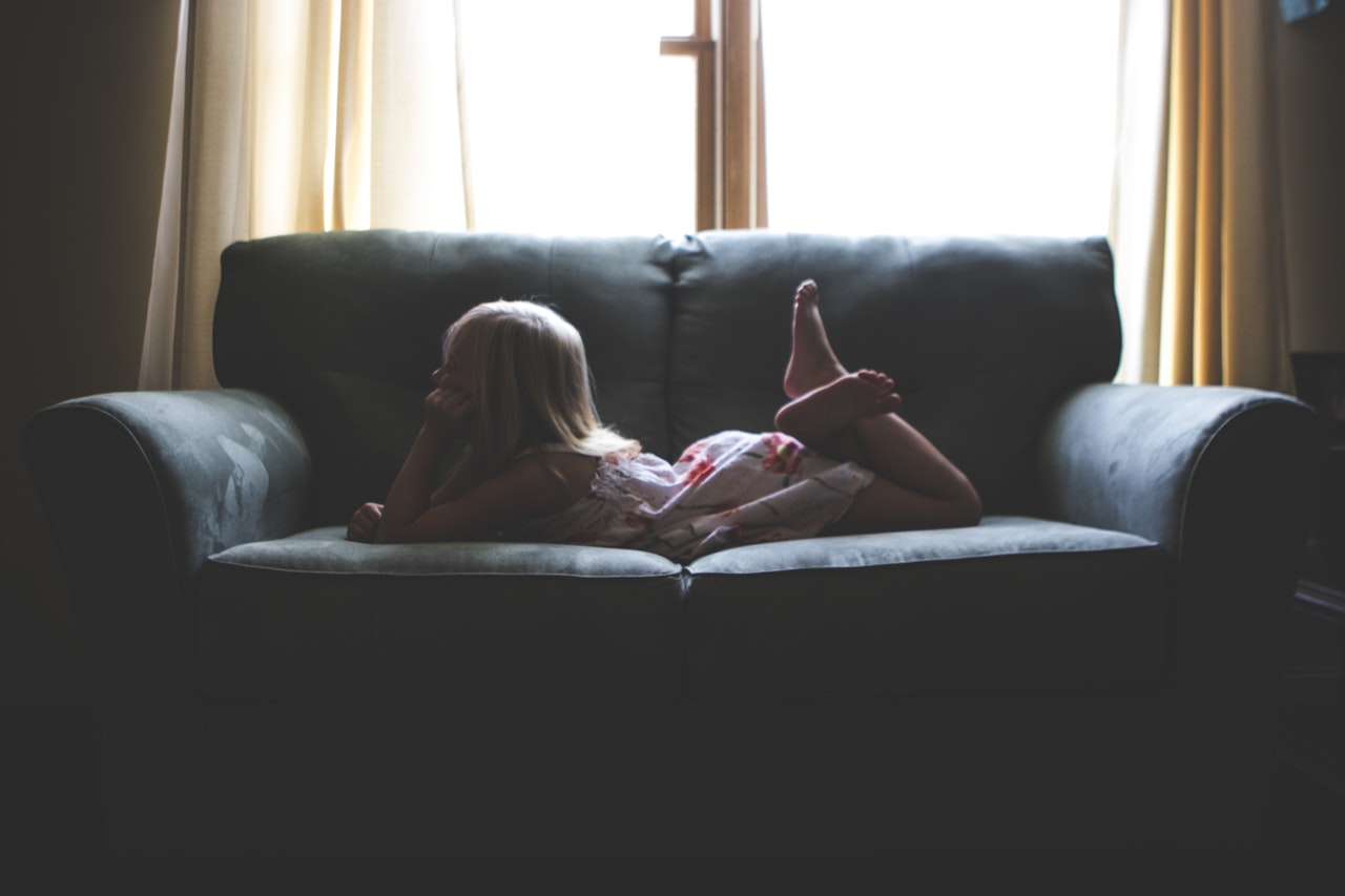 girls laying on couch in front of window