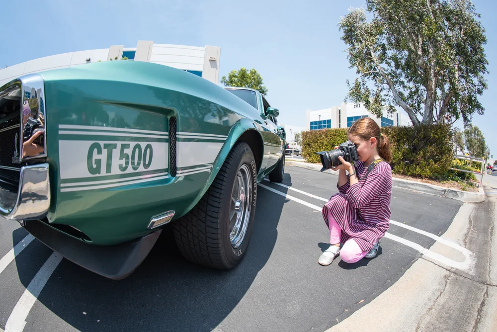 girl using nikon to take picture of an old car