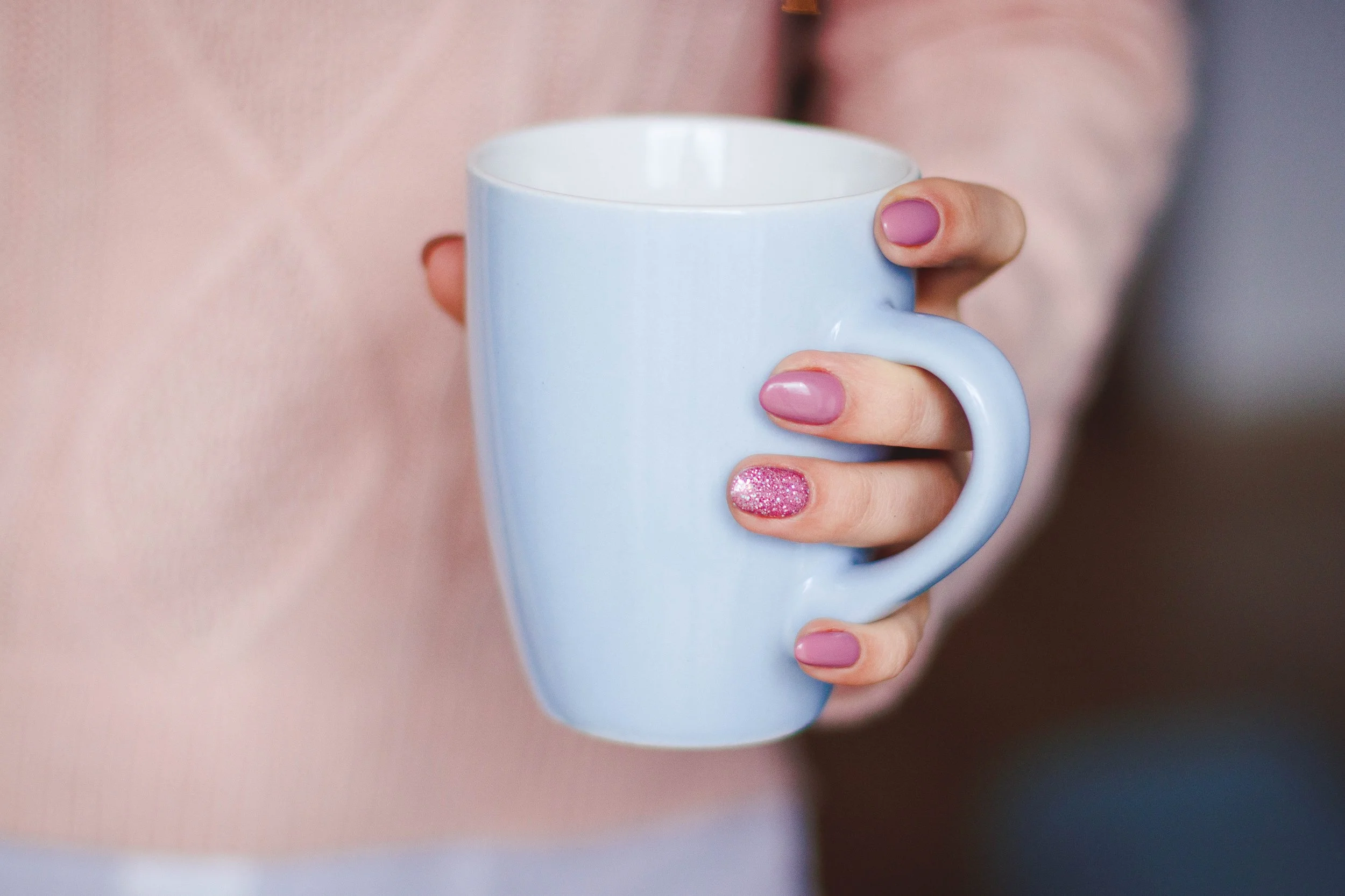 manicured hand holding a cup of tea