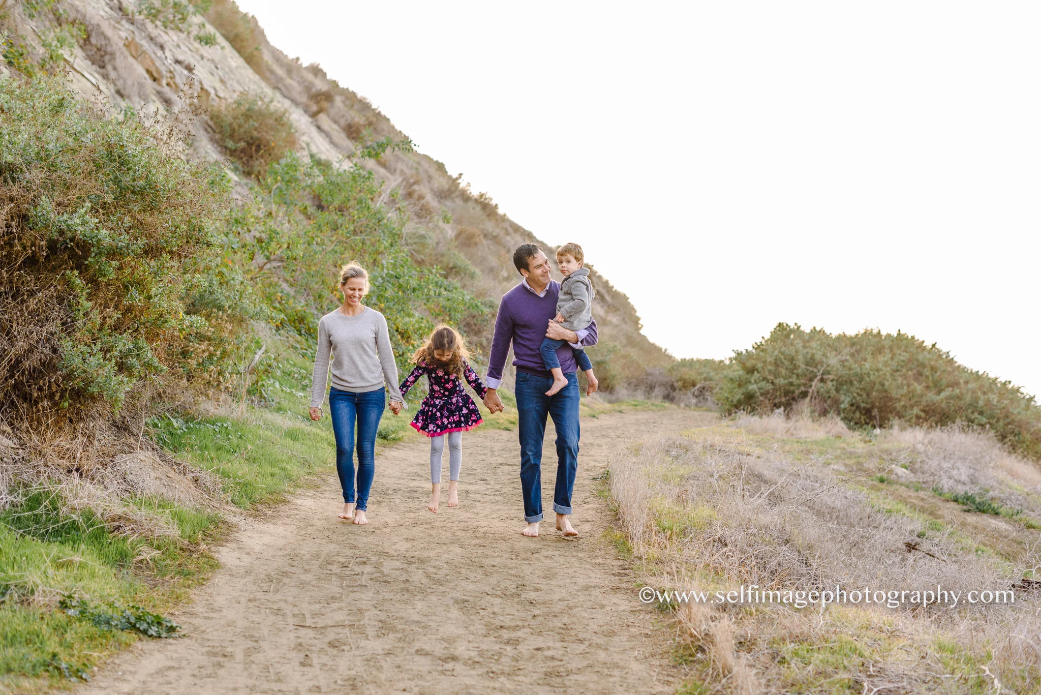 family walking on a path together while holding hands
