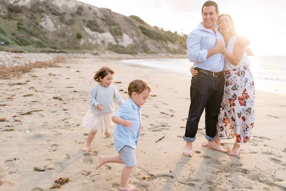 Family playing at the beach during sunset
