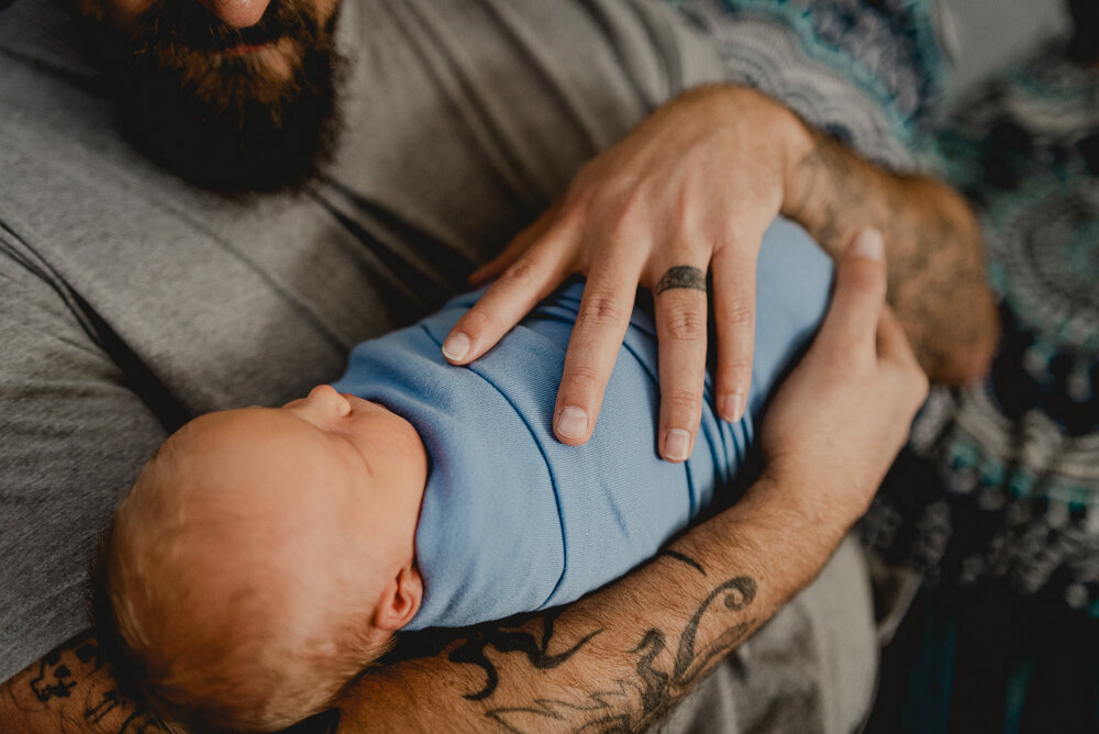 Dad with tattoos holding newborn baby boy