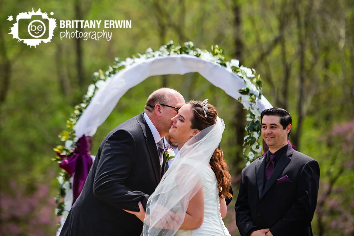 Father-of-the-bride-handing-off-with-cheek-kiss-outdoor-ceremony-groom-reaction.jpg