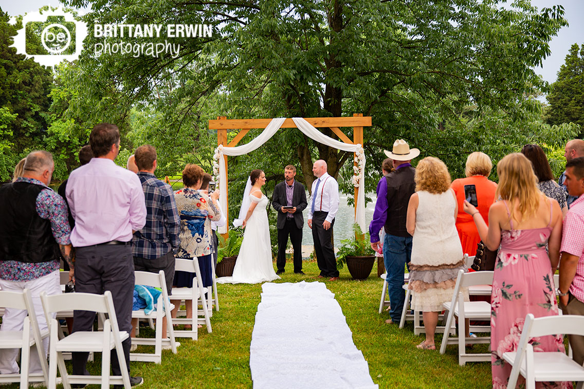 Wedding-ceremony-photographer-couple-at-altar-wooden-arbor-with-white-drapery.jpg