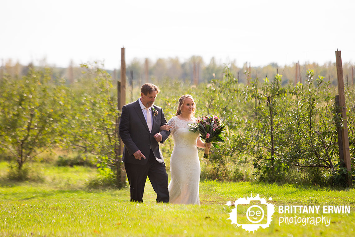 Wedding-photographer-bride-walking-down-aisle-with-father-orchard-apple-tree.jpg