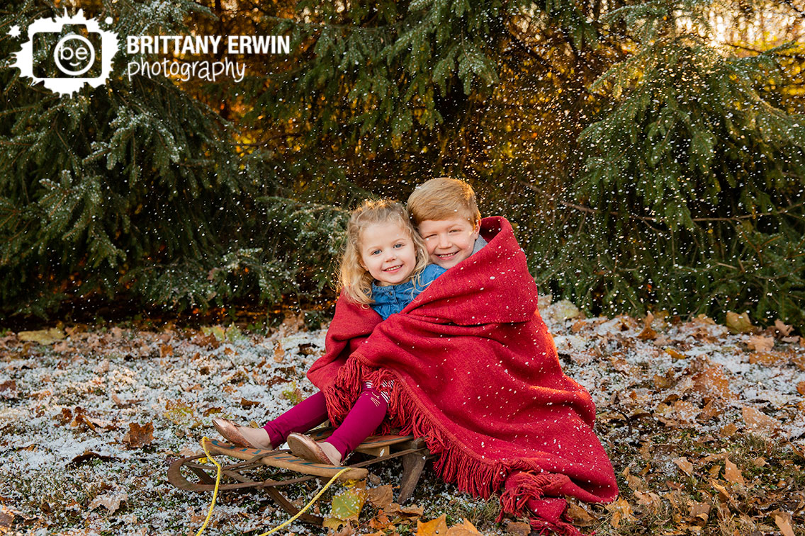 Snow-portrait-session-mini-photographer-brother-sister-snuggled-in-blanket-snowing-sled.jpg