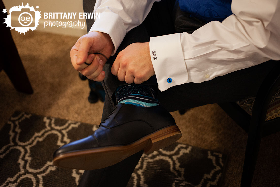 Indianapolis-wedding-photographer-groom-tying-shoes-water-cufflinks-blue-socks-initial-cuffs.jpg