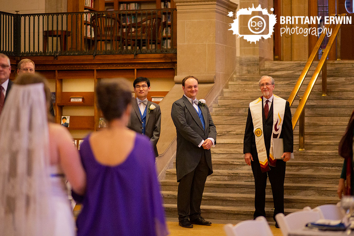 Indianapolis-central-library-wedding-ceremony-photographer-groom-reaction-bride-walking-down-aisle-with-mother-and-father.jpg