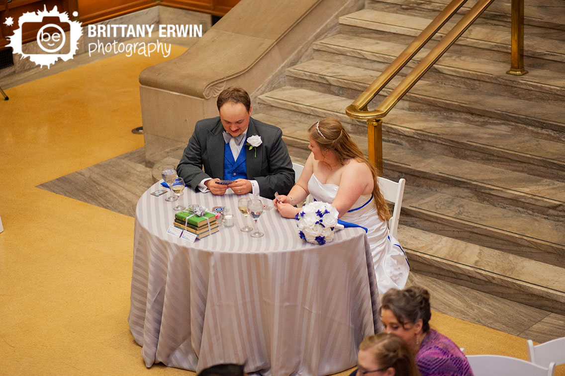 Indianapolis-central-library-wedding-photographer-first-game-couple-at-sweetheart-head-table-playing-cards.jpg