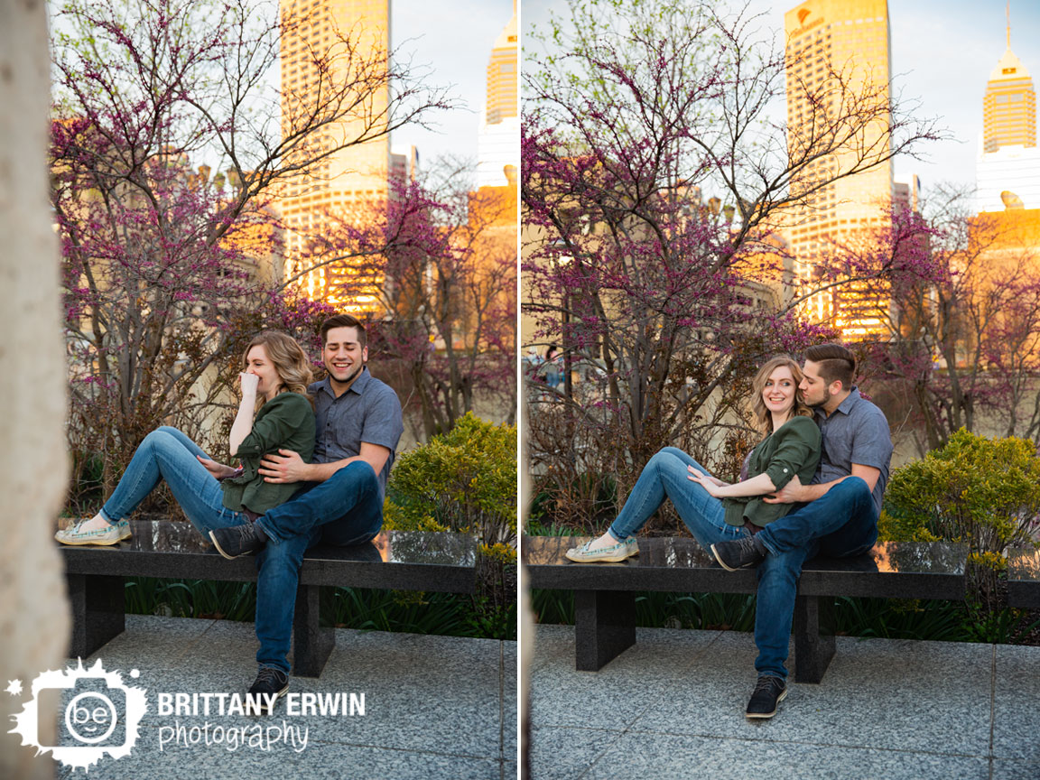 Indianapolis-skyline-portrait-engagement-photographer-couple-laugh-on-bench-spring-blooming-tree.jpg