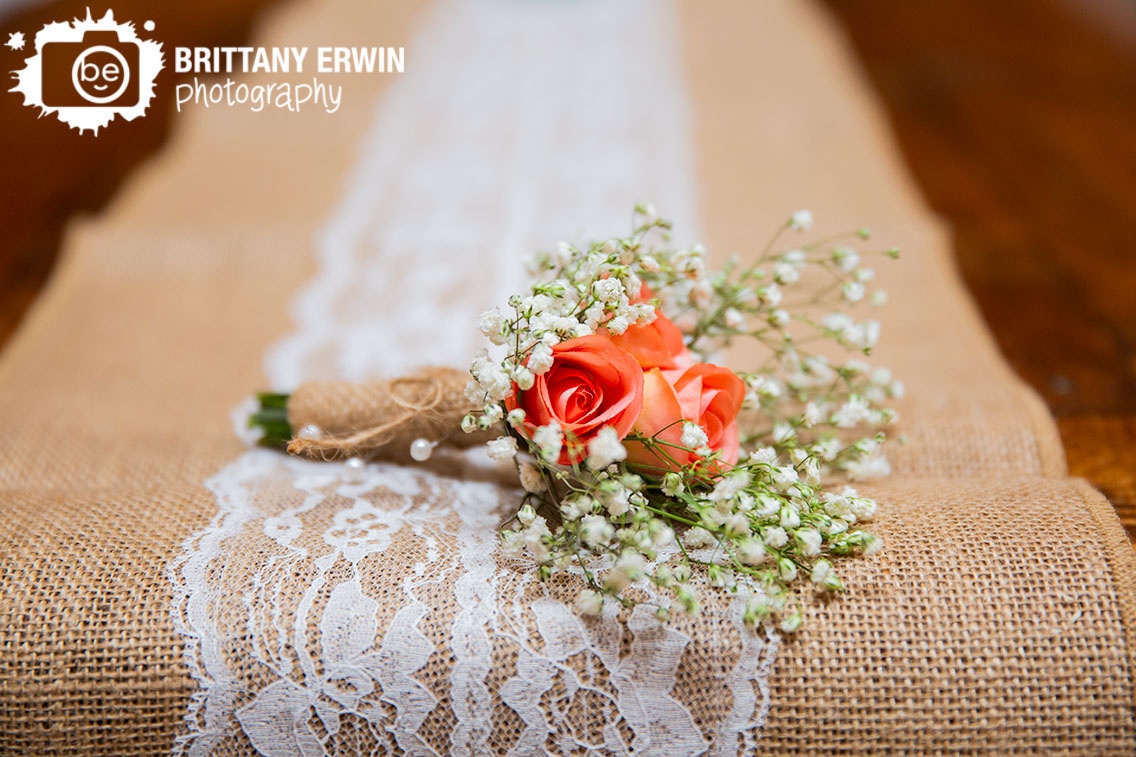 handmade-boutonniere-for-groom-made-with-pink-roses-and-babys-breath-resting-on-burlap-and-lace-table-runner.jpg