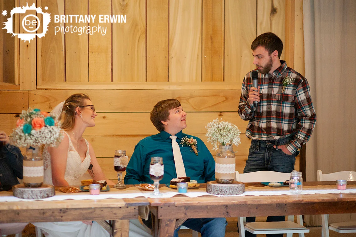 Rustic-Gatherings-LLC-wedding-barn-venue-couple-at-head-table-toast-by-best-man.jpg