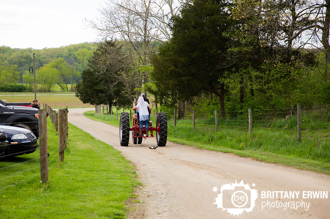 Bride-and-groom-exit-on-red-antique-tractor-can-string.jpg