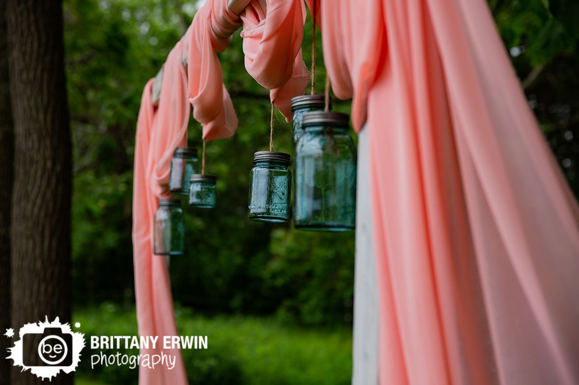 mason-jar-hanging-from-arbor-wedding-altar-space-pink-drapery.jpg