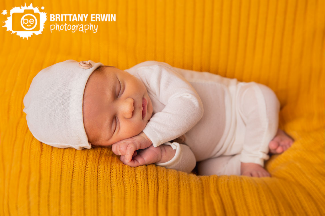 Indianapolis-newborn-studio-portrait-photographer-mustard-blanket-sleepy-boy-white-outfit-with-hat-buttons.jpg