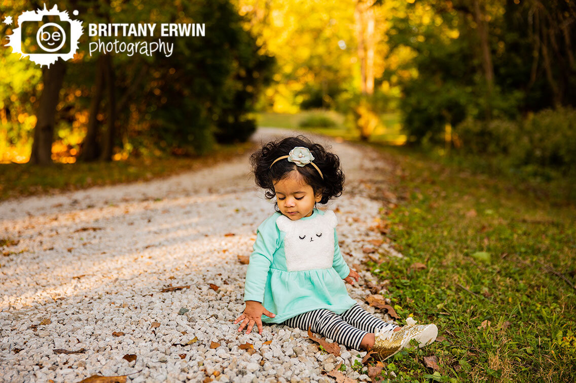 Fall-milestone-portrait-photographer-baby-girl-sitting-on-gravel-path.jpg