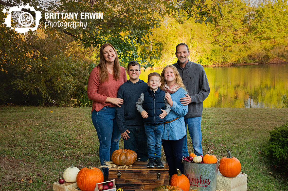 Fall-mini-session-family-portrait-photographer-pumpkins-with-leaves-by-pond.jpg