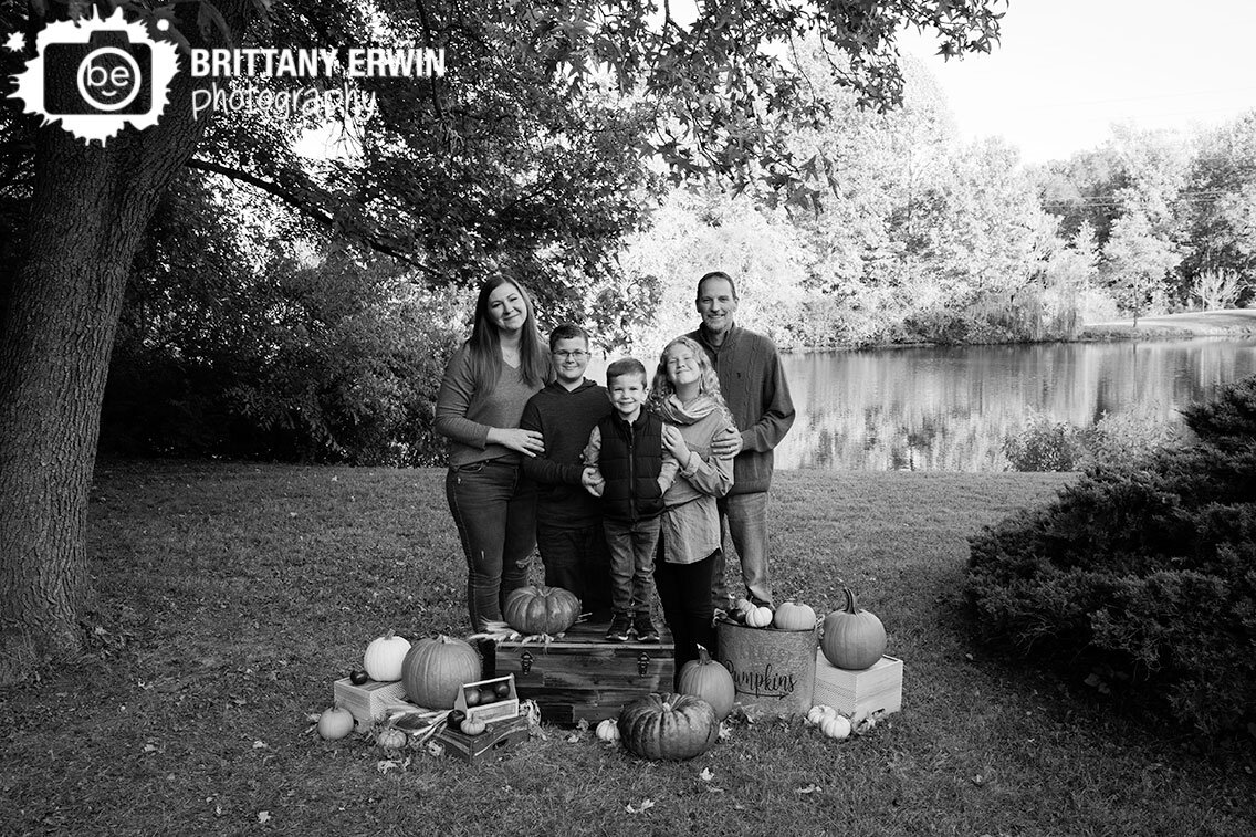 Indianapolis-family-portrait-photographer-group-with-wooden-trunk-pumpkins-by-pond.jpg