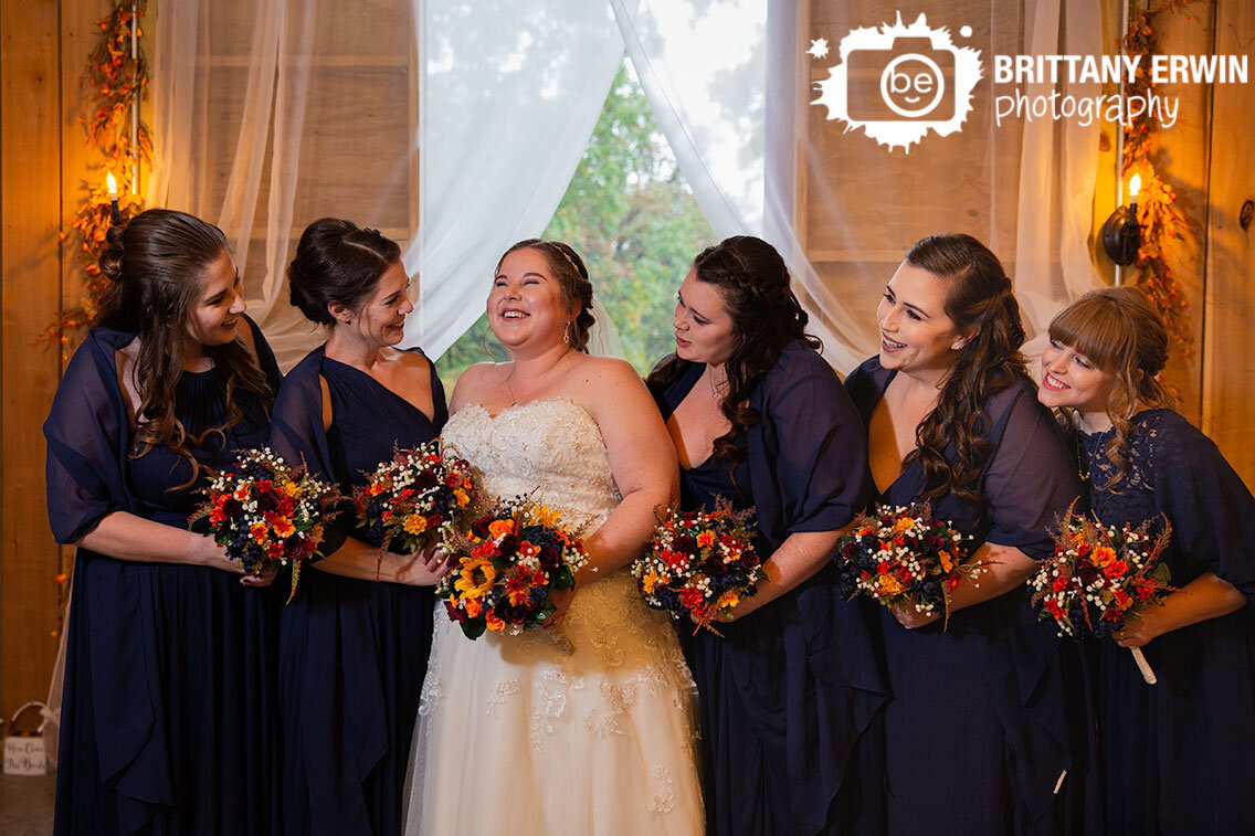 bride-with-bridesmaids-group-portrait-in-barn-wedding-laughing.jpg