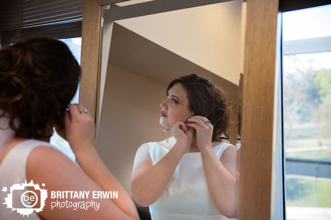 bride-getting-ready-putting-on-earrings-in-mirror.jpg