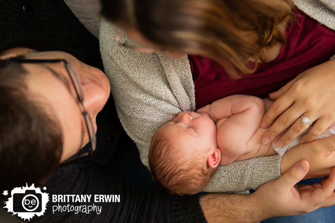 parents-holding-sleeping-baby-boy-newborn-in-home-lifestyle-photographer.jpg