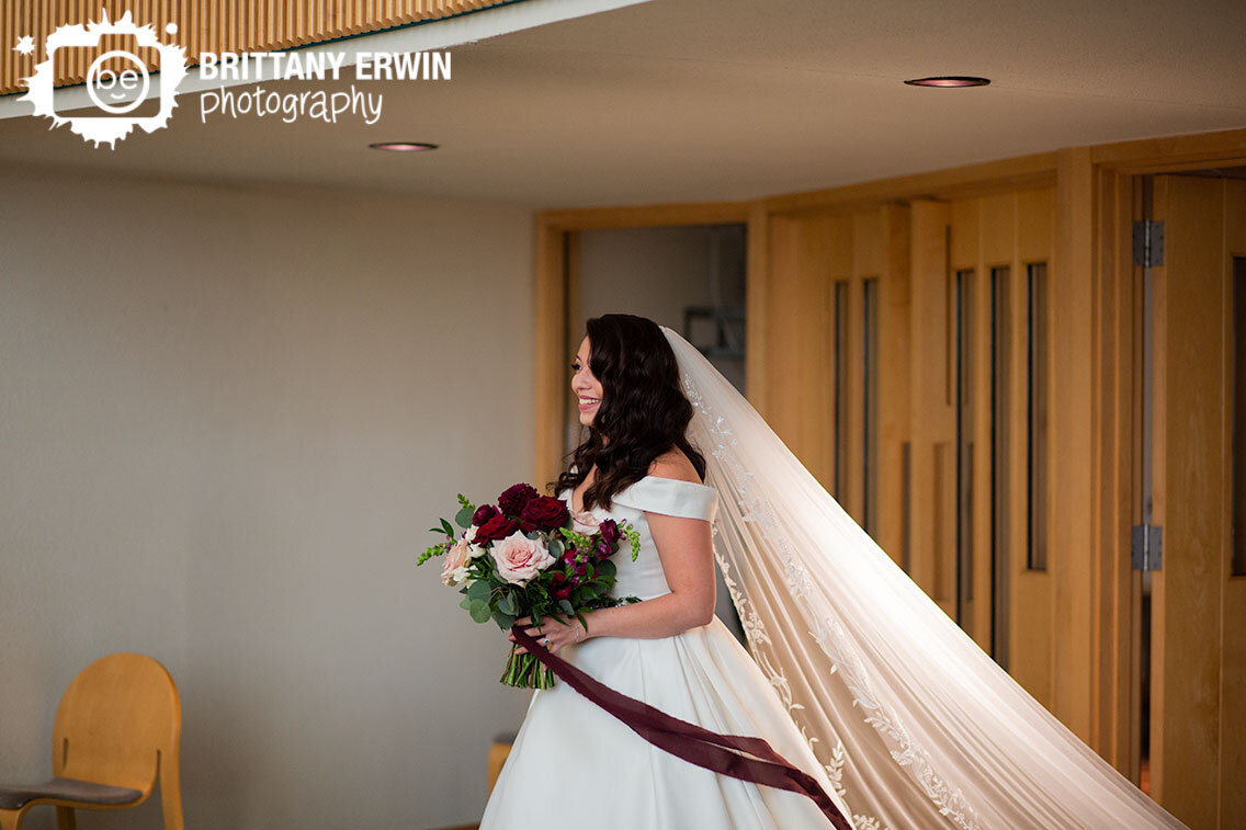 Bride-reacting-to-seeing-groom-walking-down-aisle-long-burgundy-ribbon-veil.jpg