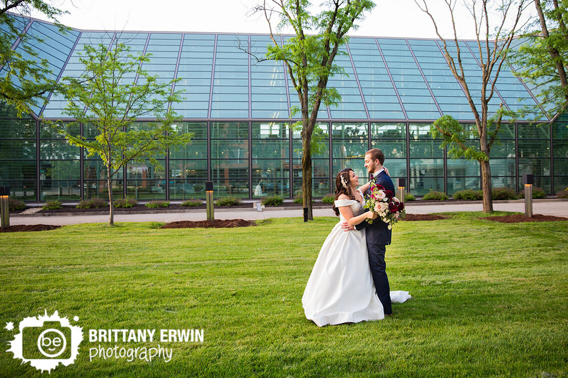 Columbus-Indiana-wedding-photographer-bride-groom-dance-in-field-by-glass-building.jpg