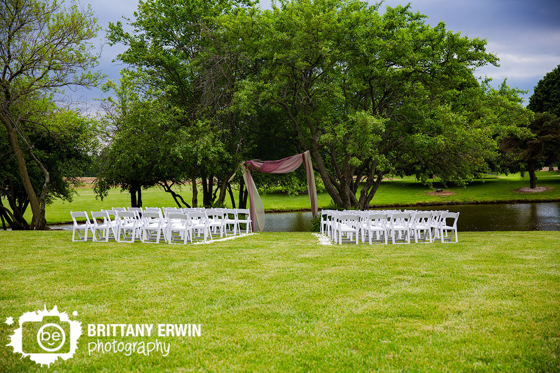 backyard-wedding-ceremony-setup-at-water-side-with-drapery-in-trees-white-chairs.jpg