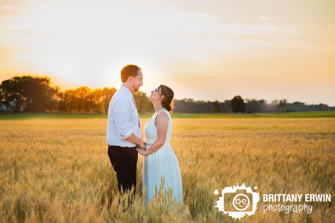 Indiana-backyard-wedding-photographer-couple-in-hay-field-at-sunset-holding-hands.jpg