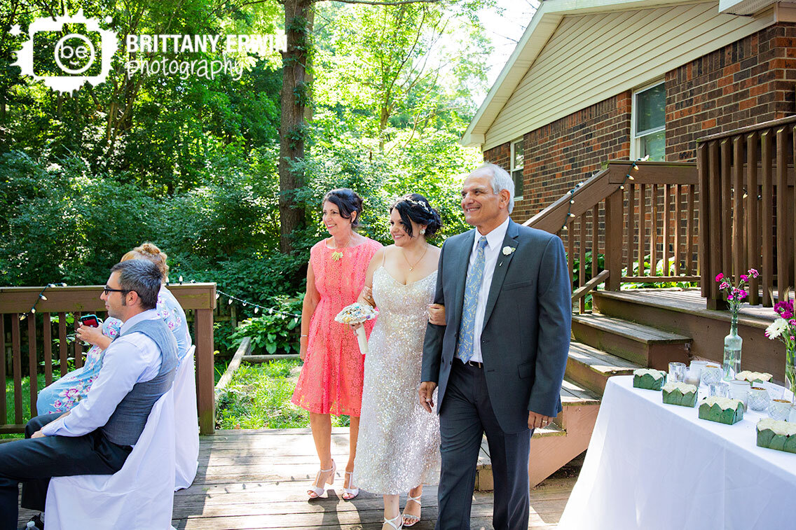 Bride-walking-down-aisle-with-mother-and-father-parents-outdoor-backyard-wedding-ceremony.jpg