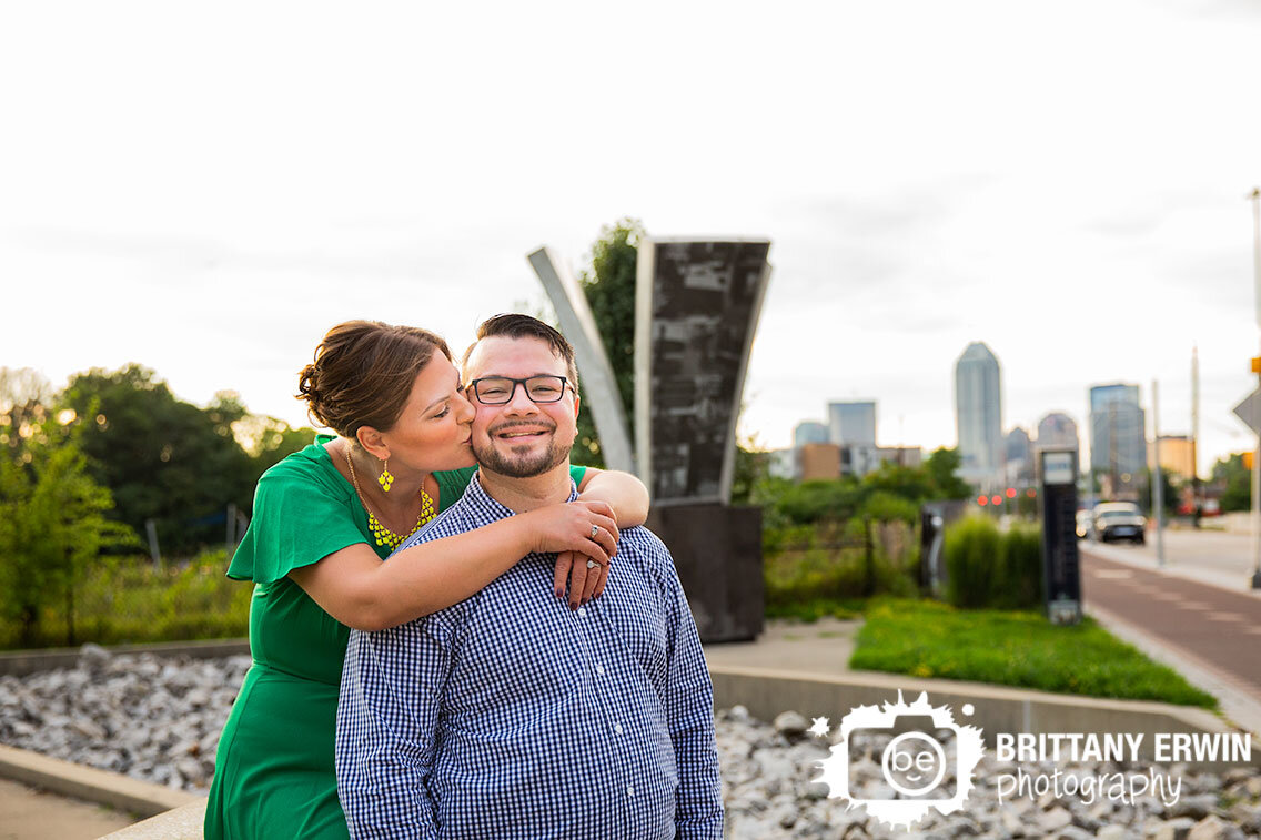 Indianapolis-skyline-from-Fountain-Square-Indiana-engagement-portrait-photographer-couple-cheek-kiss.jpg