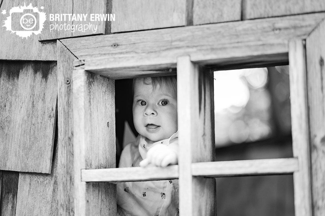 baby-girl-peeking-through-window-wood-sculpture-house.jpg