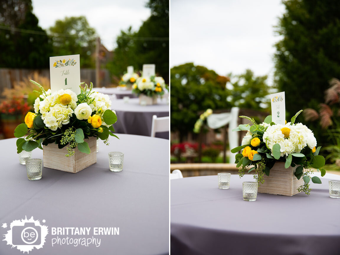 Backyard-wedding-reception-table-setup-with-wood-box-centerpiece-with-yellow-flowers-ceremony-altar-behind.jpg