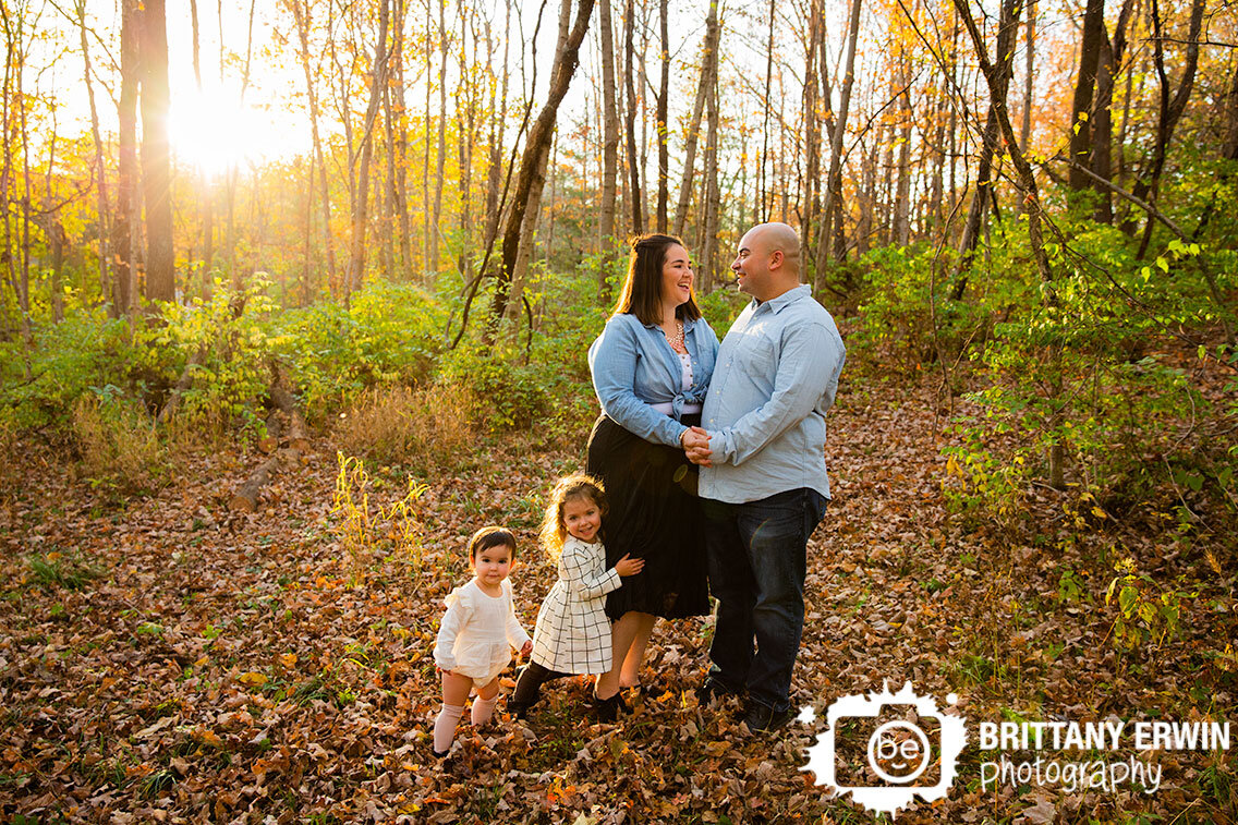 Fall-family-portrait-photographer-couple-in-leaves-with-daughters-sunset.jpg