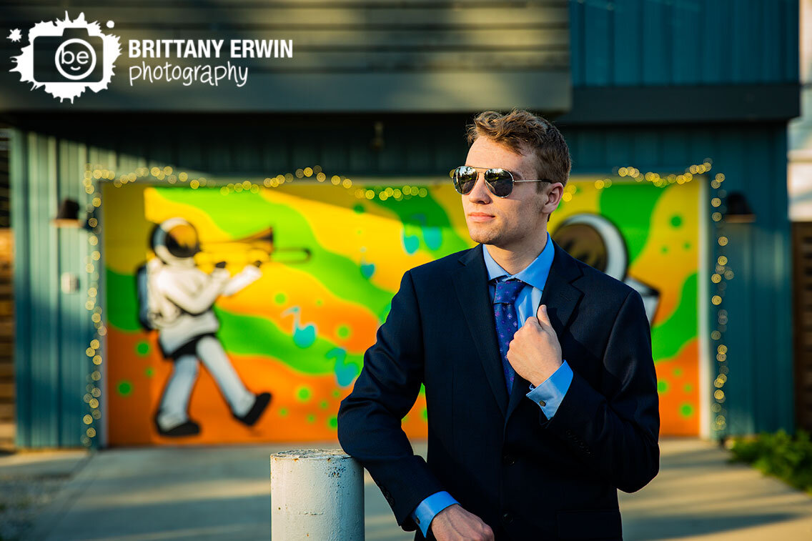 Senior-portrait-photographer-suit-and-tie-aviator-sunglasses-with-musician-astronaut-mural.jpg