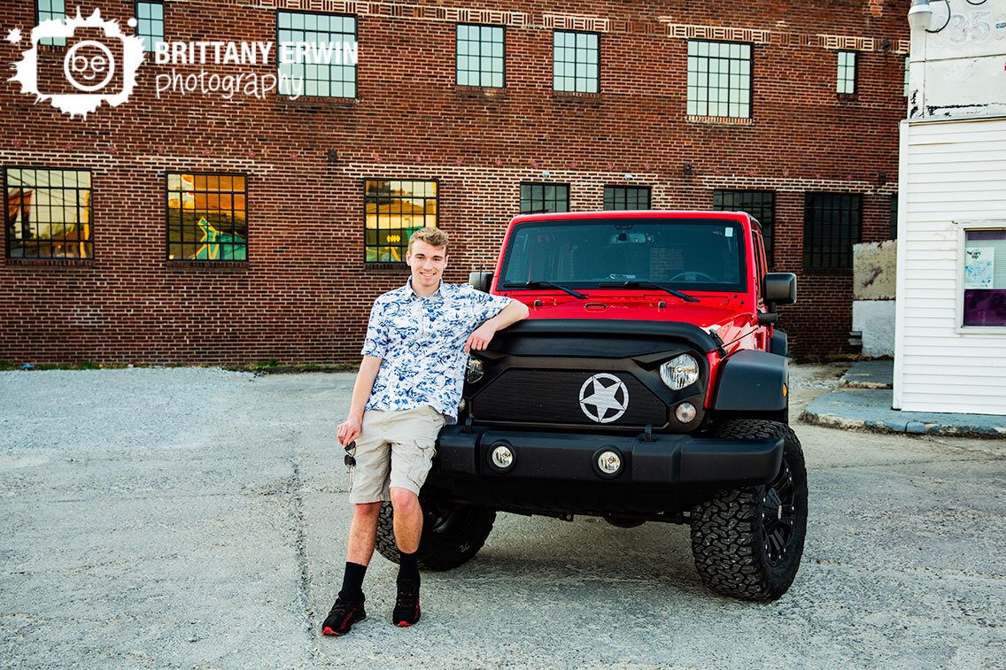 Fountain-Square-Indiana-senior-portrait-photographer-boy-with-red-jeep-in-parking-lot-with-brick-building.jpg