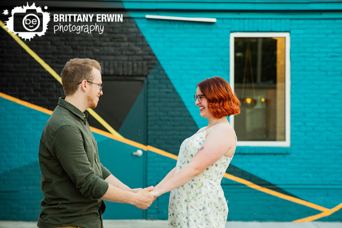 Fountain-Square-Indiana-engagment-portrait-photographer-couple-with-mural-laughing.jpg