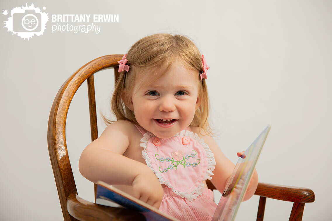 toddler-girl-heirloom-pink-outfit-in-antique-rocking-chair-reading-a-book.jpg