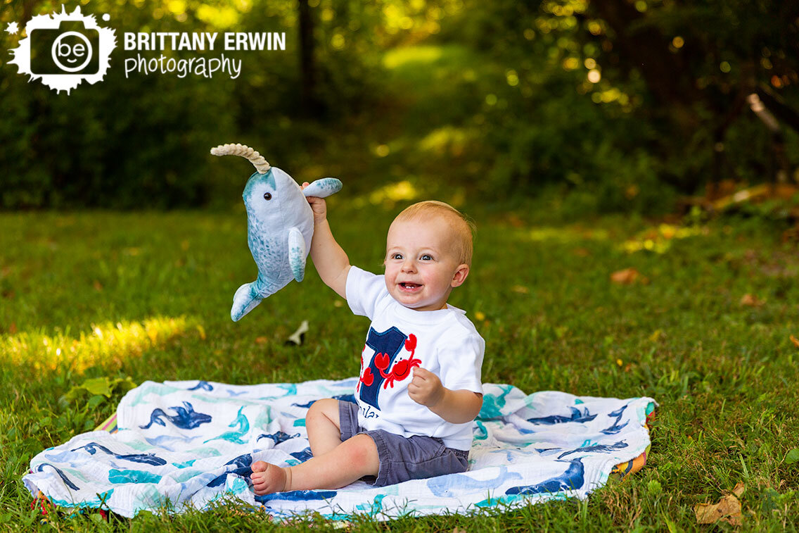 Indianapolis-portrait-photographer-boy-toddler-playing-with-stuffed-narwhal-on-whale-blanket-outdoor-session.jpg
