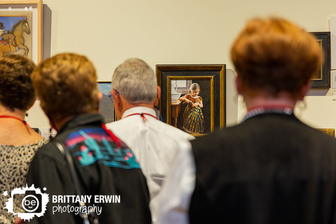 Indianapolis-event-photographer-Quest-for-the-West-miniature-art-sale-wall-of-paintings-guests-viewing.jpg