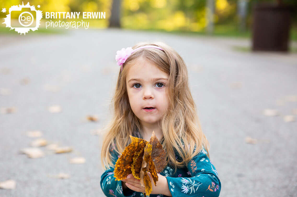 Indianapolis-portrait-photographer-girl-collecting-yellow-fallen-leaves-outside.jpg