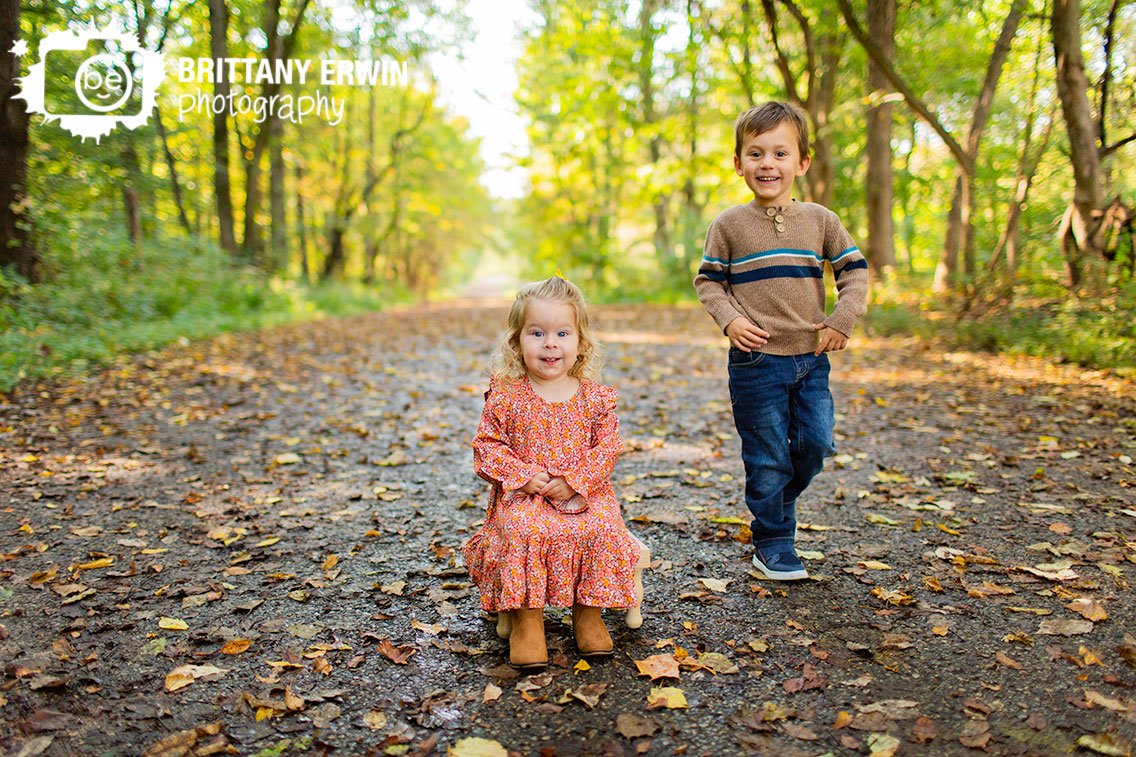 brother-sister-outside-fall-portrait-photographer-leaf-covered-path.jpg