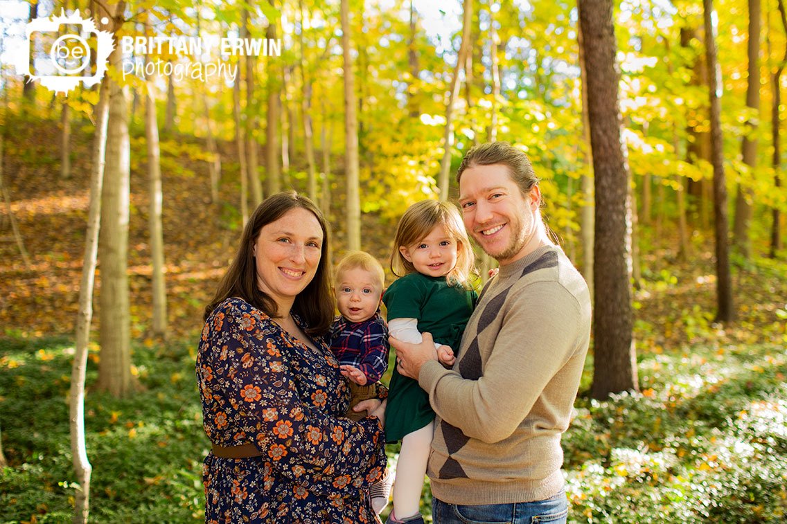 Indianapolis-fall-family-portrait-photographer-parents-holding-brother-sister-with-leaves-on-ground.jpg