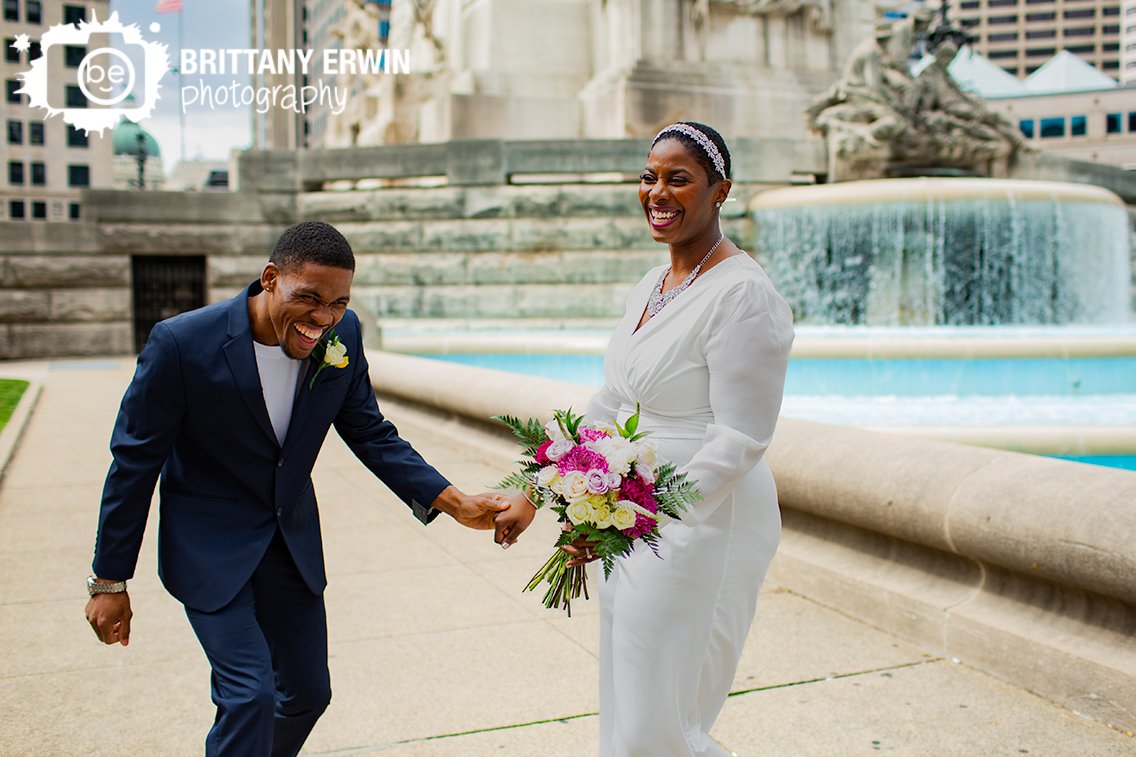 fun-couple-on-monument-circle-bridal-portrait-laughing-by-fountain.jpg